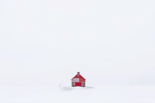 Lone red farm building in a snowy Iowa field