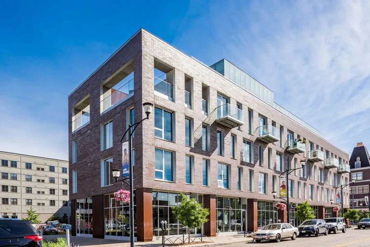 Modern mixed-use apartment building on a sunny street corner