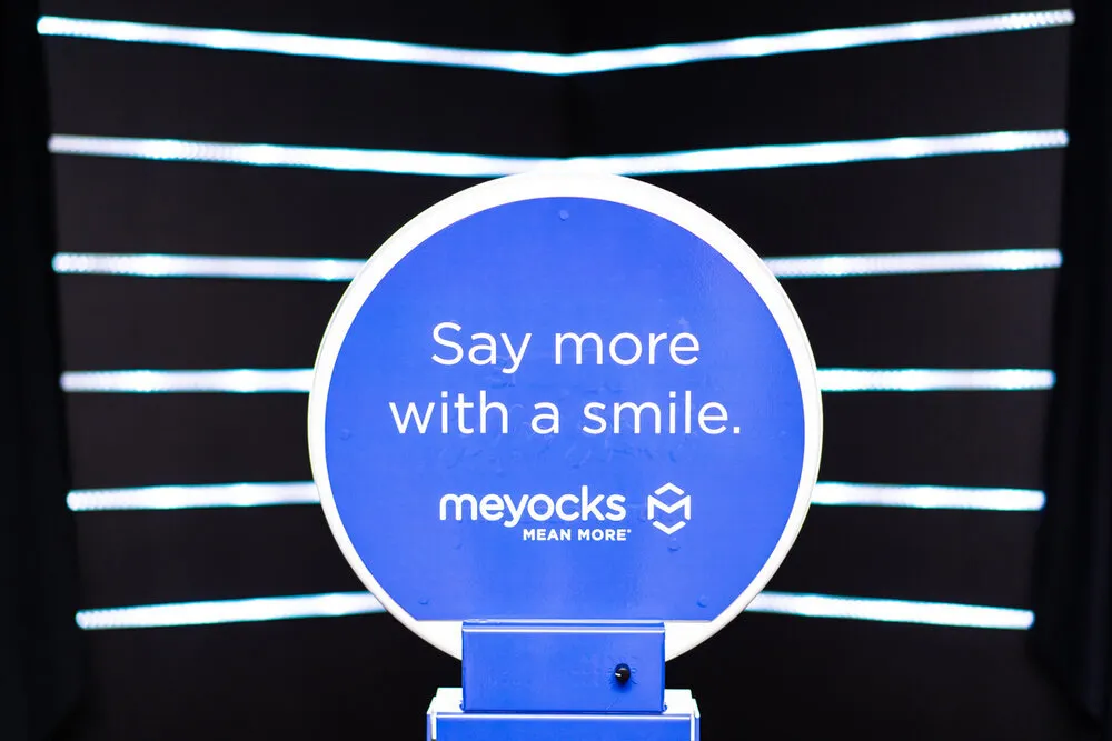 Illuminated "Say more with a smile" sign at a branded event