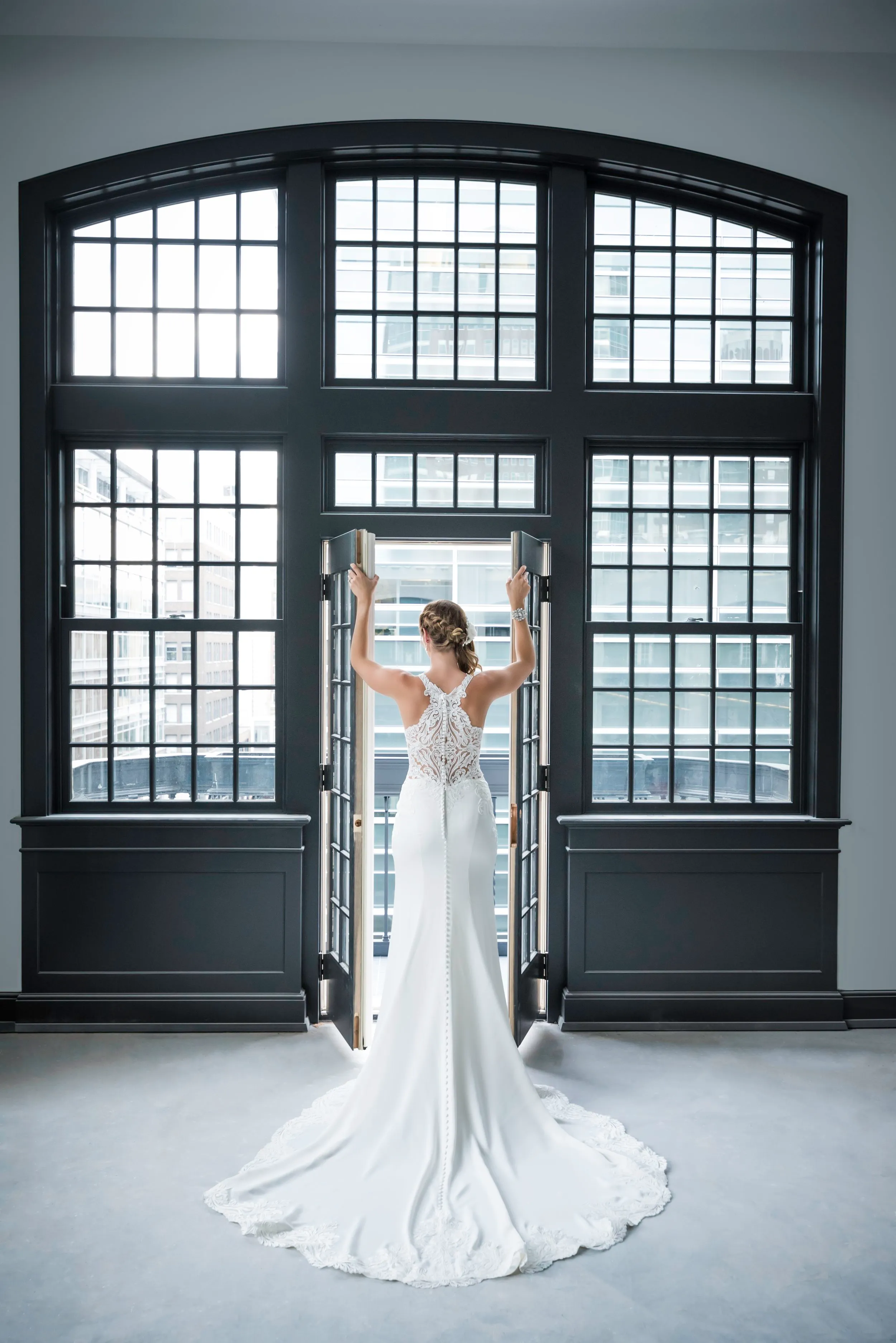 Bride standing before a tall arched window