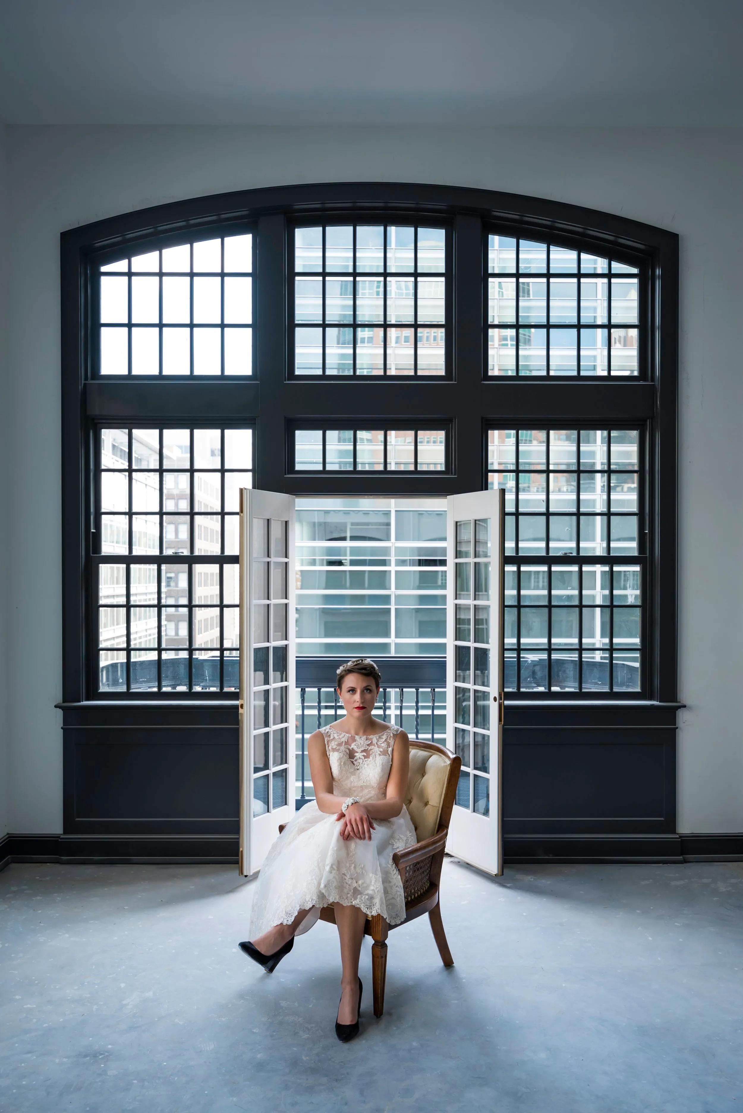 Bride seated before a tall arched window