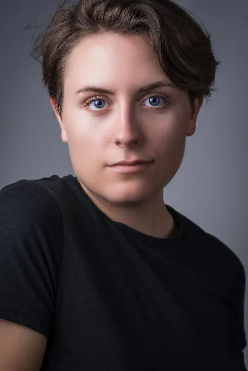 Studio portrait of a young woman in a black shirt against a gray backdrop