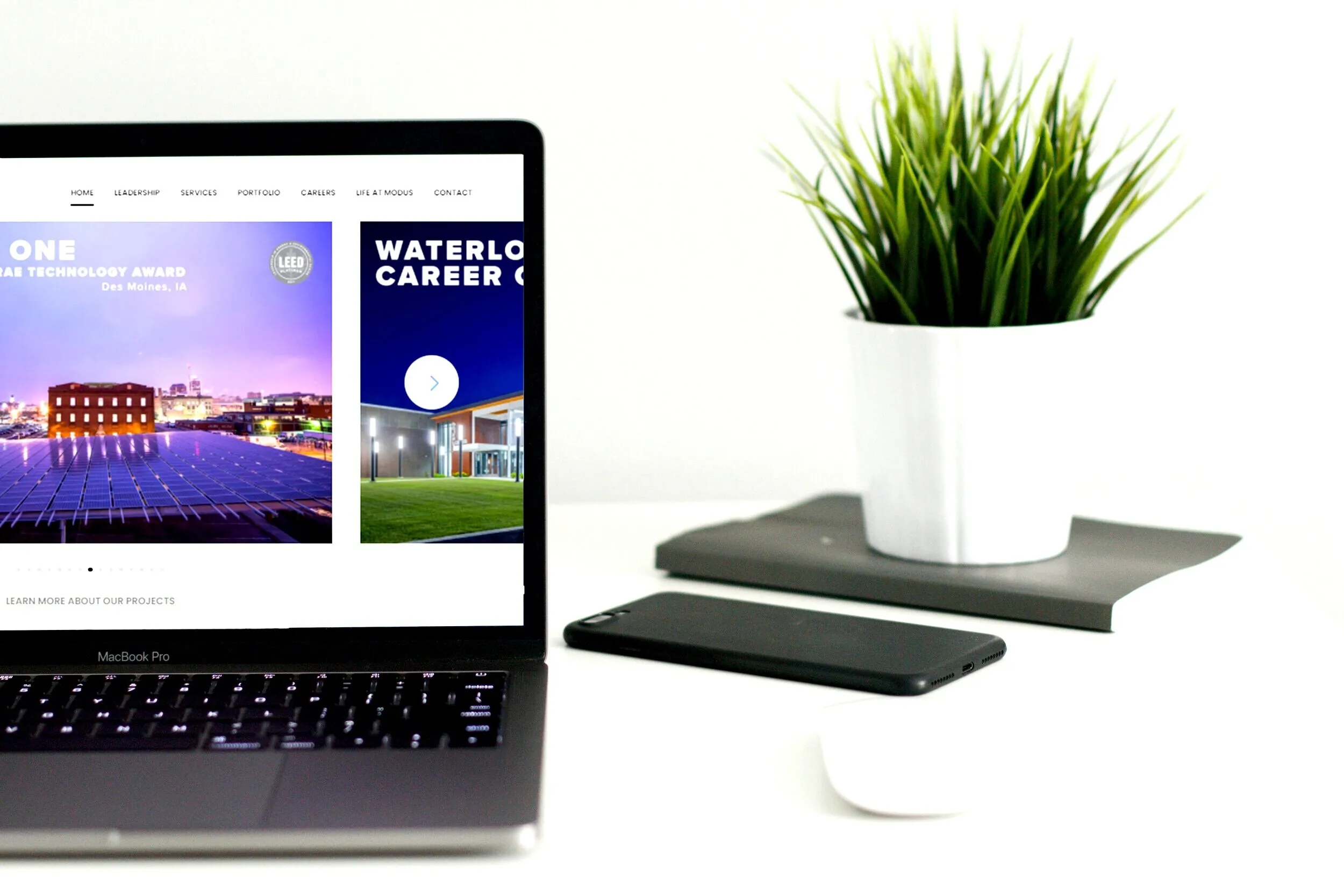 Laptop displaying a client website on a minimalist desk with a plant