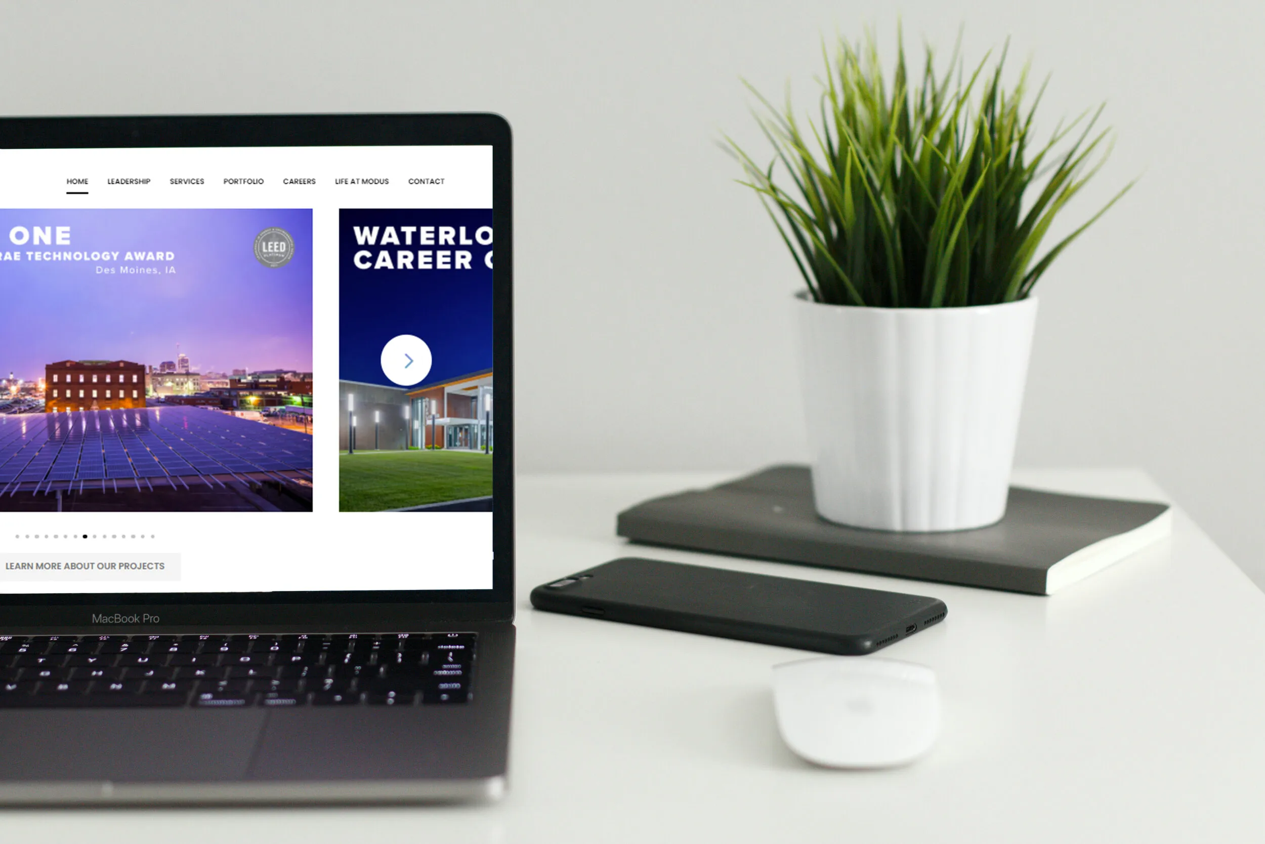 Laptop displaying a client website on a minimalist desk with a plant